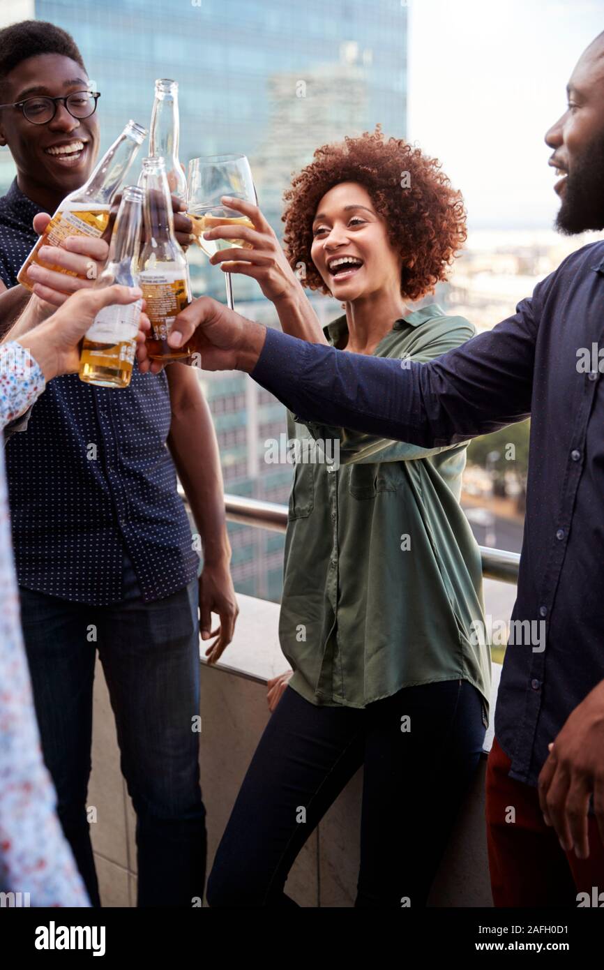 Sorridente azienda creativa ai colleghi di bere dopo i lavori di sollevamento vetri per fare un brindisi, verticale Foto Stock