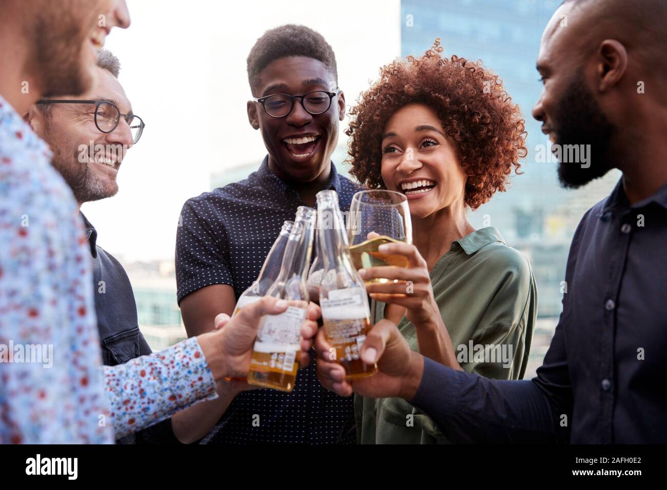 Felice creative colleghi di lavoro avente un drink dopo il lavoro sollevare gli occhiali per fare un brindisi Foto Stock