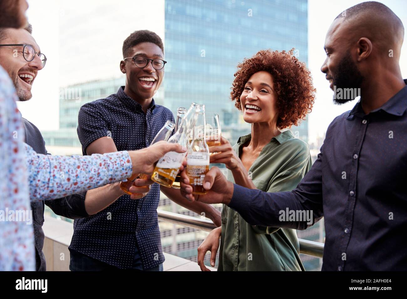Sorridente azienda creativa ai colleghi di bere dopo i lavori di sollevamento vetri per fare un brindisi Foto Stock