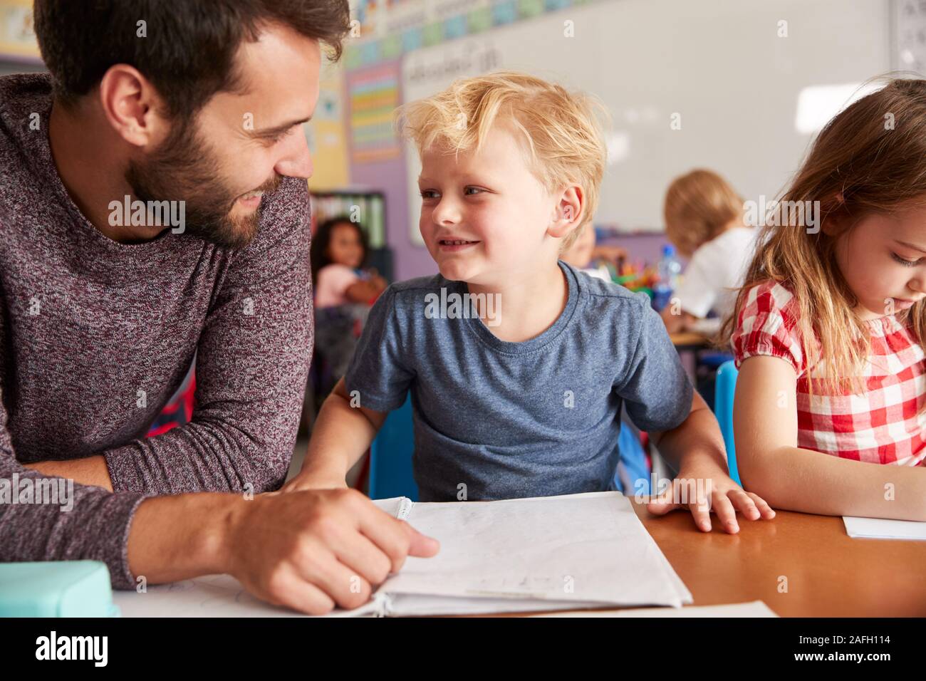 Insegnante di scuola elementare dando pupilla maschio da uno a un supporto in aula Foto Stock