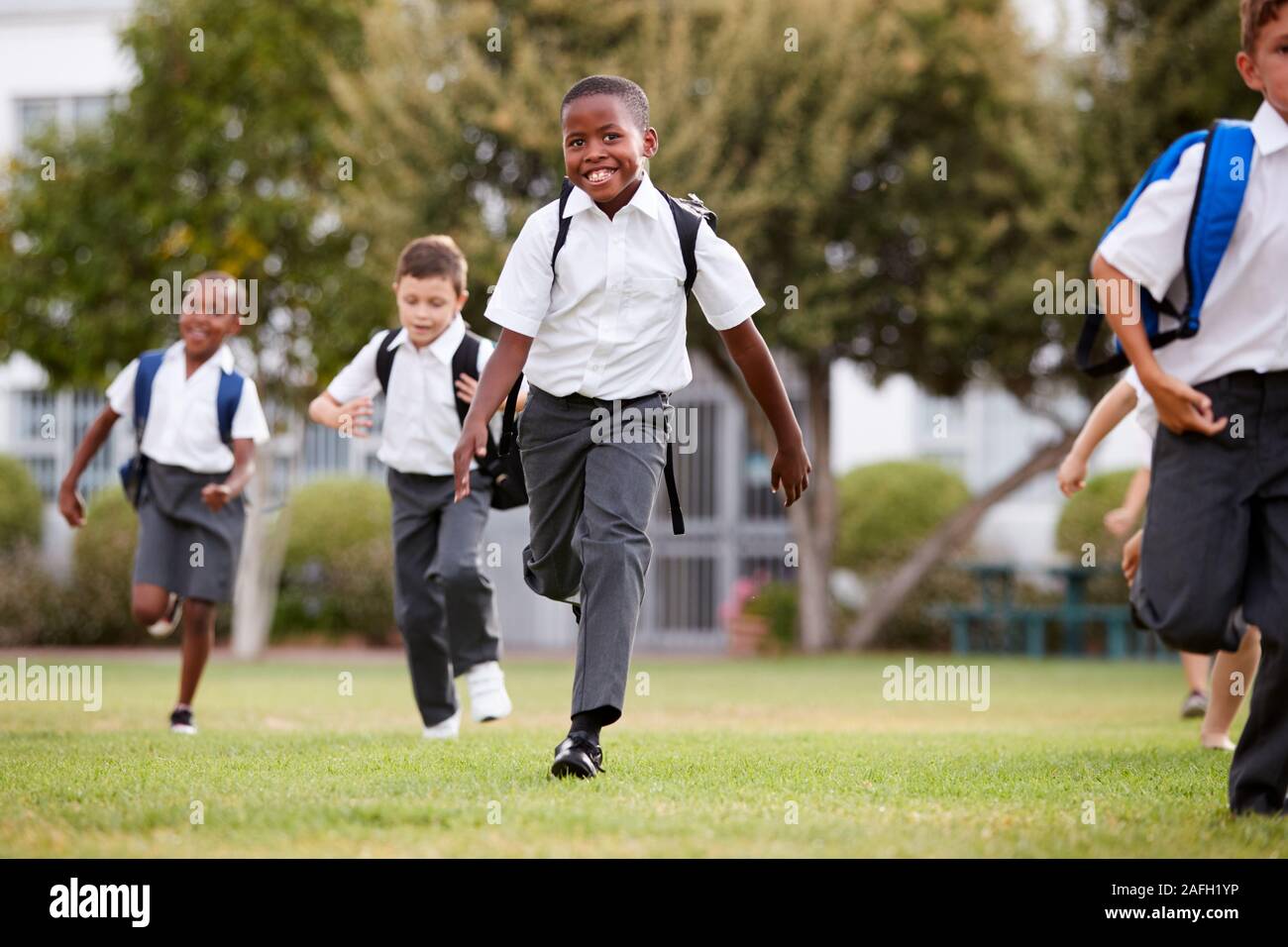 Entusiasta della scuola elementare di alunni che indossa in esecuzione uniforme su tutto il campo al tempo di interruzione Foto Stock