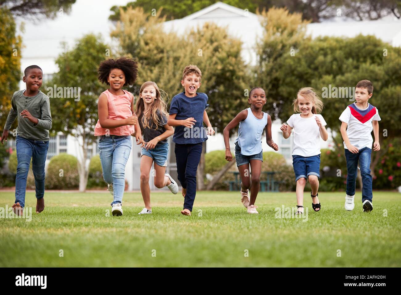 Eccitato Scuola Elementare gli alunni che attraversano il campo in corrispondenza del tempo di rottura Foto Stock