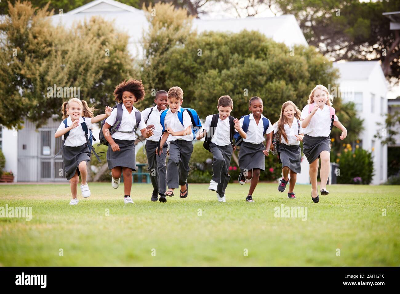 Entusiasta della scuola elementare di alunni che indossa in esecuzione uniforme su tutto il campo al tempo di interruzione Foto Stock