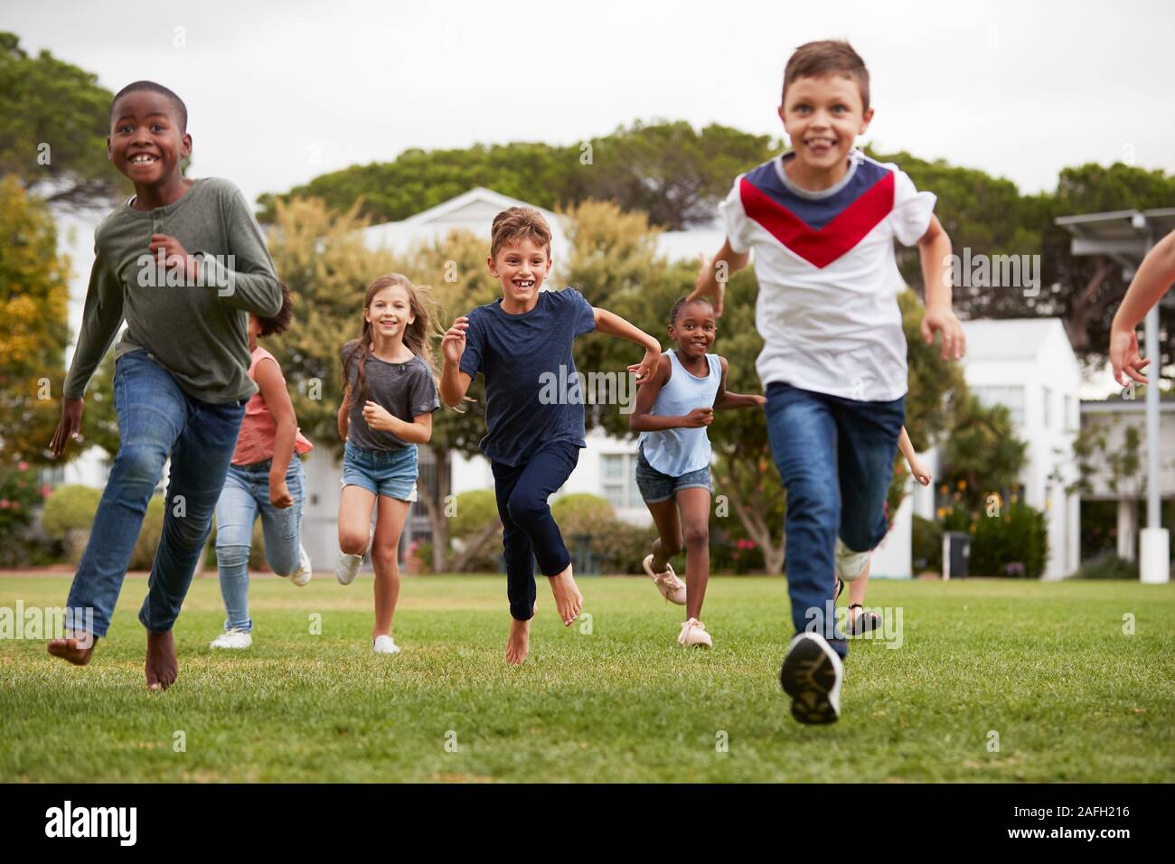 Eccitato Scuola Elementare gli alunni che attraversano il campo in corrispondenza del tempo di rottura Foto Stock