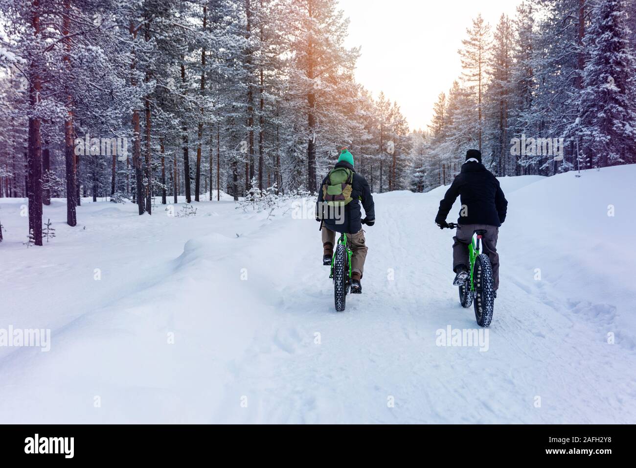 Due persone con grasso di equitazione biciclette nevoso inverno sentiero forestale in Finlandia Foto Stock