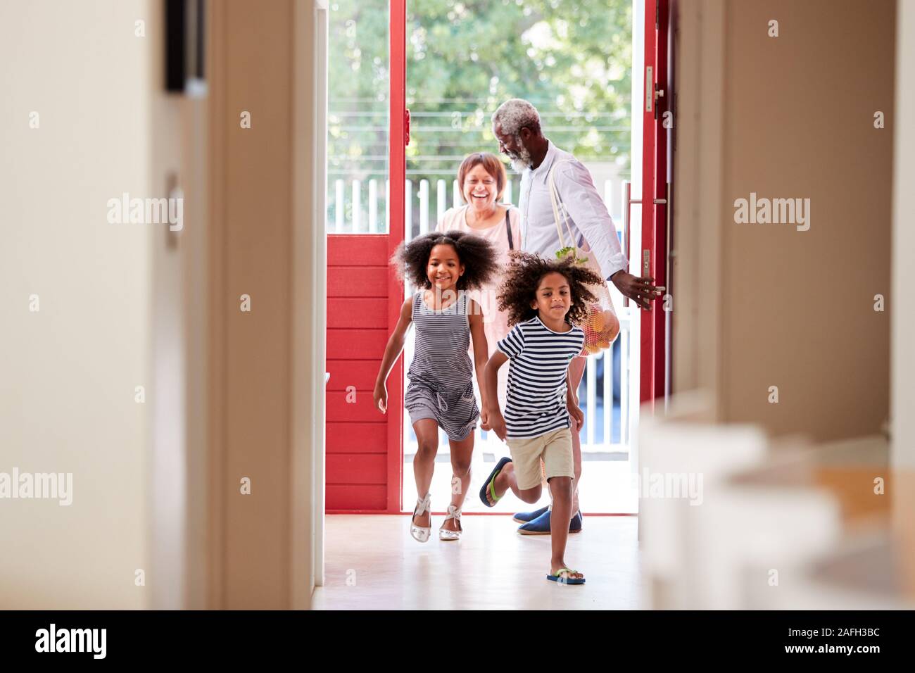 Nonni con i nipoti tornando a casa dal viaggio di Shopping trasporto Sacchetti di negozi di generi alimentari Foto Stock