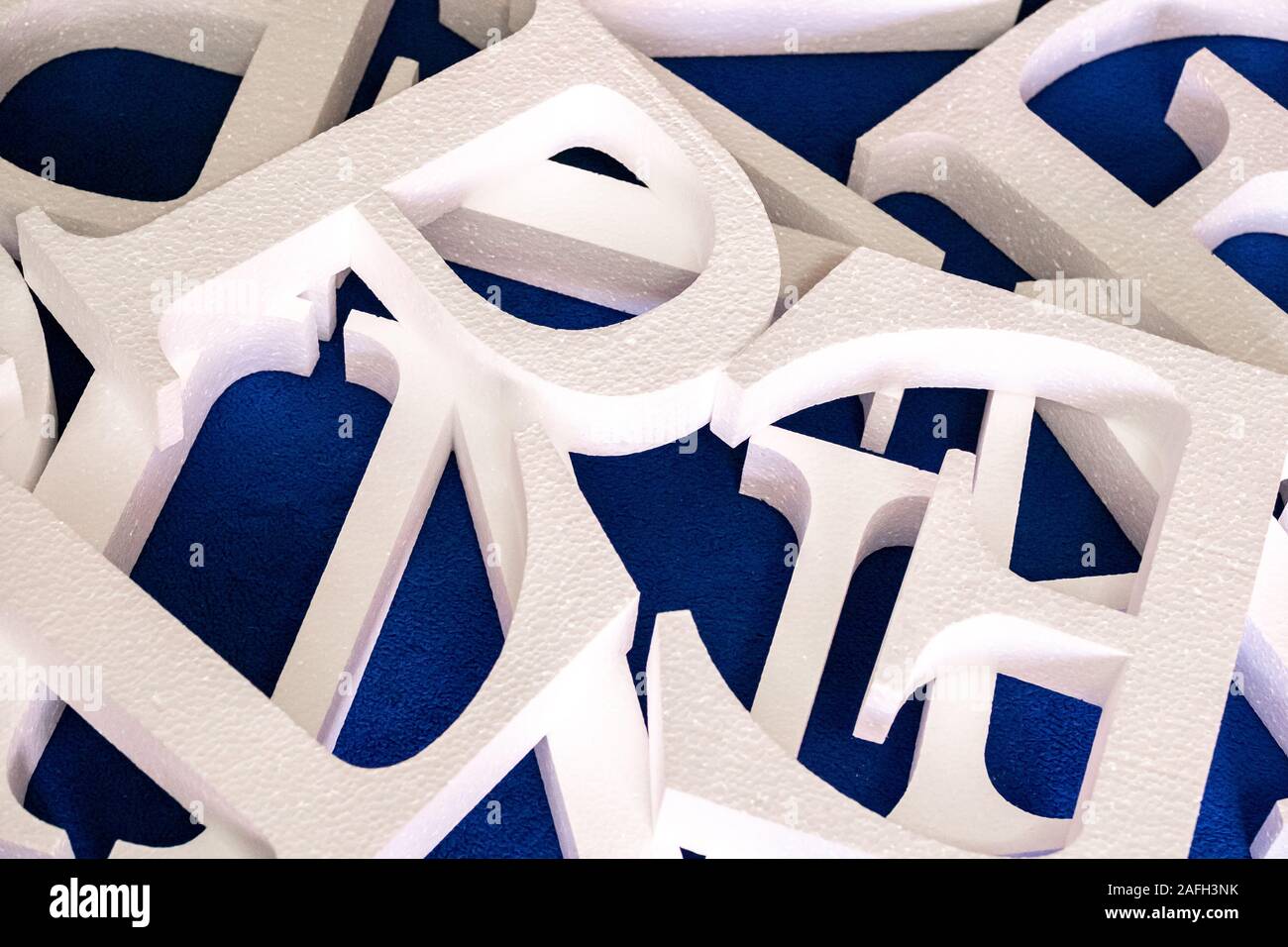 Lettere bianche tagliate fuori della schiuma senza verniciatura su uno sfondo blu. vuoto per la decorazione, rendendo il logo Foto Stock