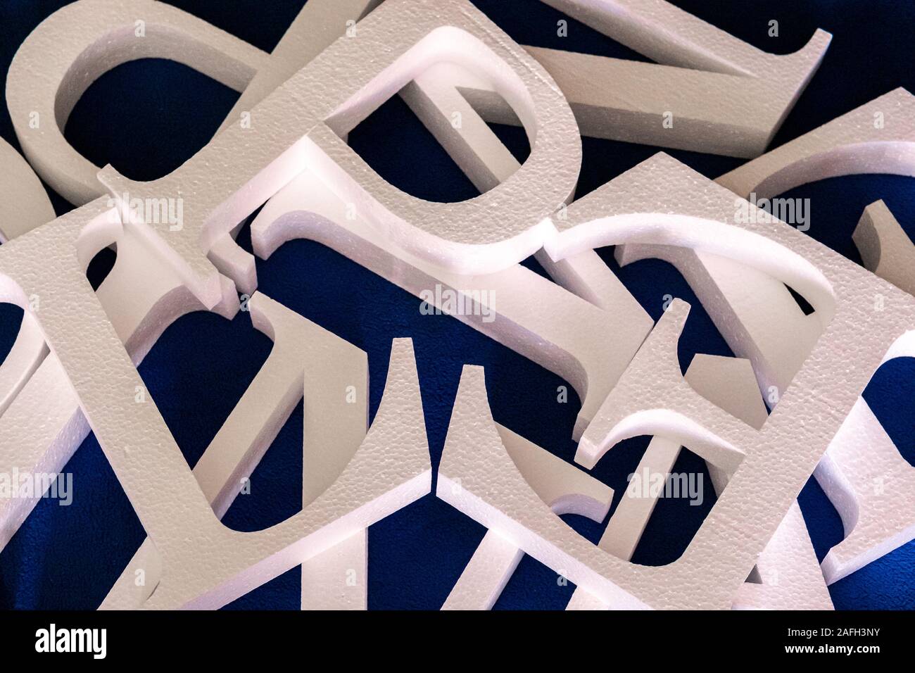 Lettere bianche tagliate fuori della schiuma senza verniciatura su uno sfondo blu. vuoto per la decorazione, rendendo il logo Foto Stock