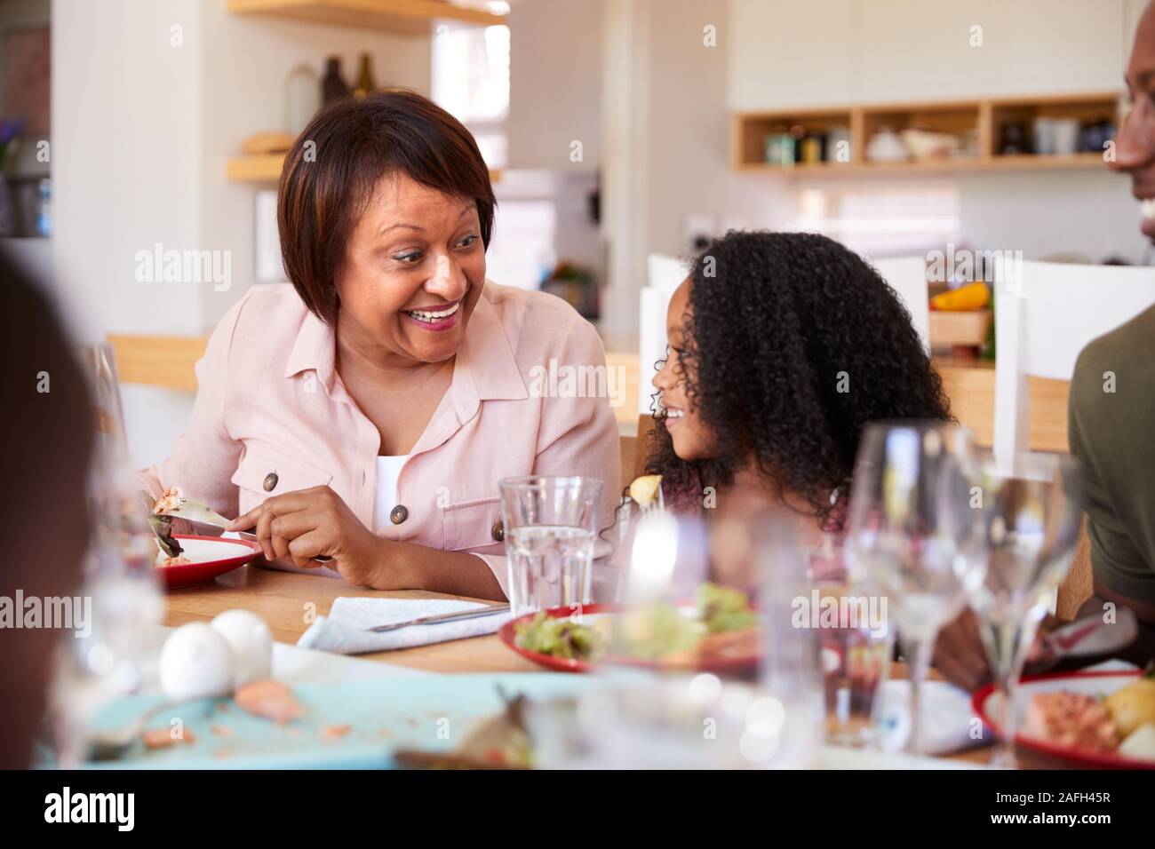 Famiglia Multi-Generation seduti attorno al tavolo di gioco a casa godendo di pasto insieme Foto Stock