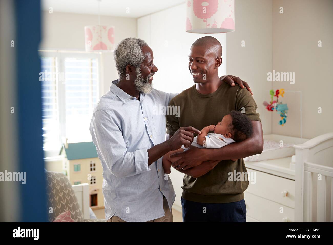 Orgogliosi di Nonno con figlio adulto coccole Baby nipote in vivaio a casa Foto Stock