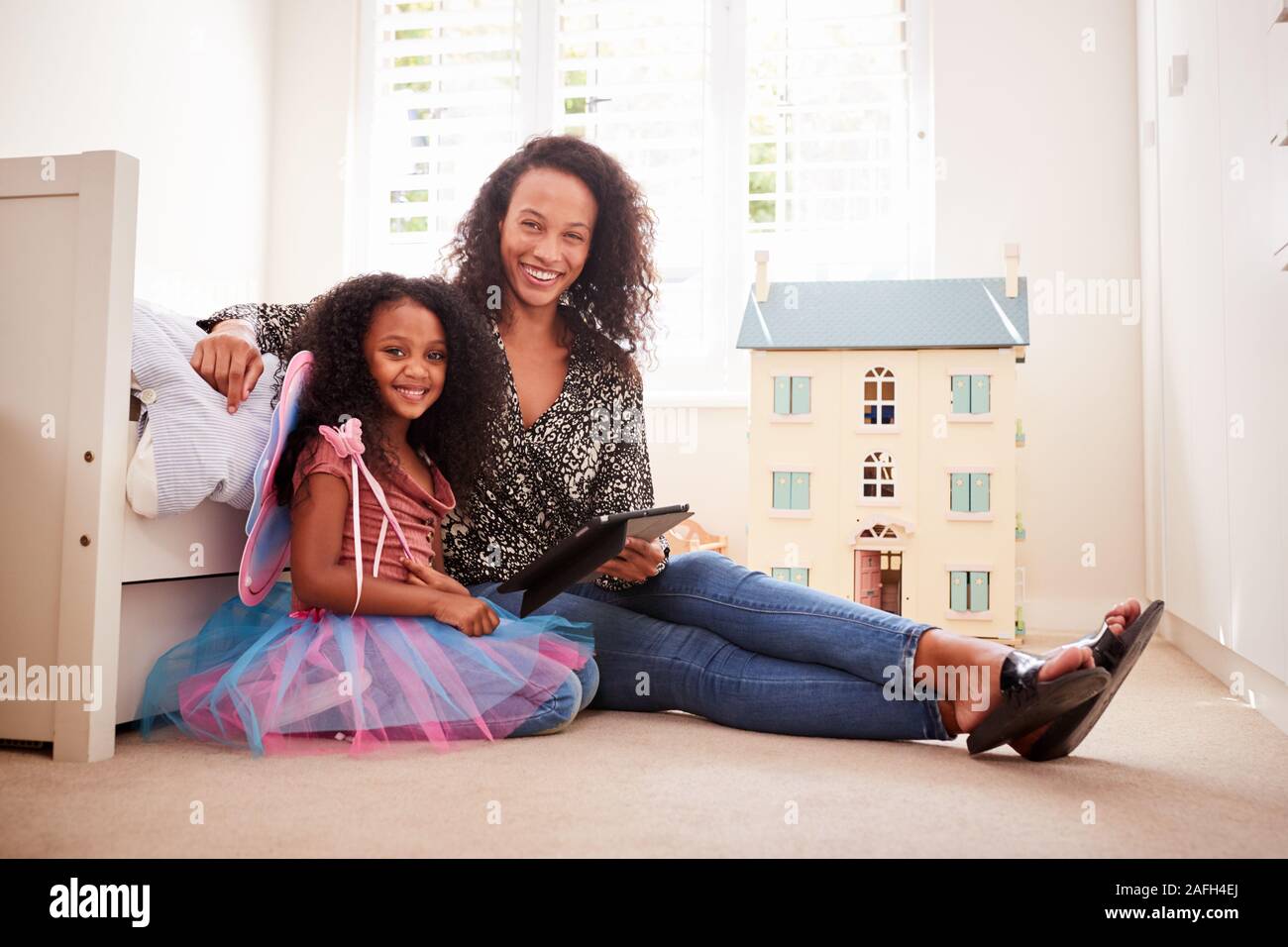 Ritratto Di madre in figlia seduta sul letto in camera da letto per i bambini con tavoletta digitale insieme Foto Stock