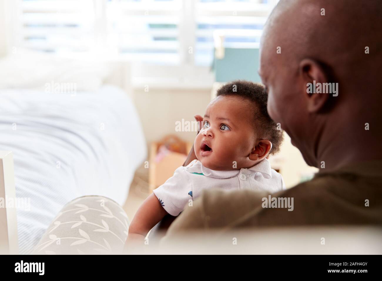 Padre orgoglioso delle coccole figlio neonato nel nido a casa Foto Stock