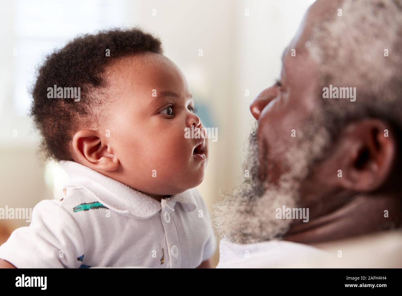 Orgogliosi di Nonno Cuddling Baby nipote in vivaio a casa Foto Stock