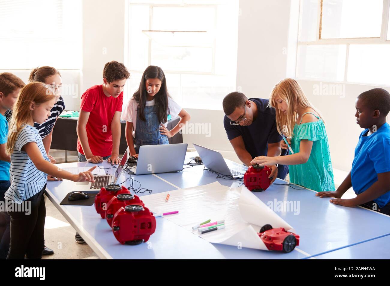 Gruppo di studenti nella scuola dopo la codifica del calcolatore classe imparare a programmare un veicolo robot Foto Stock