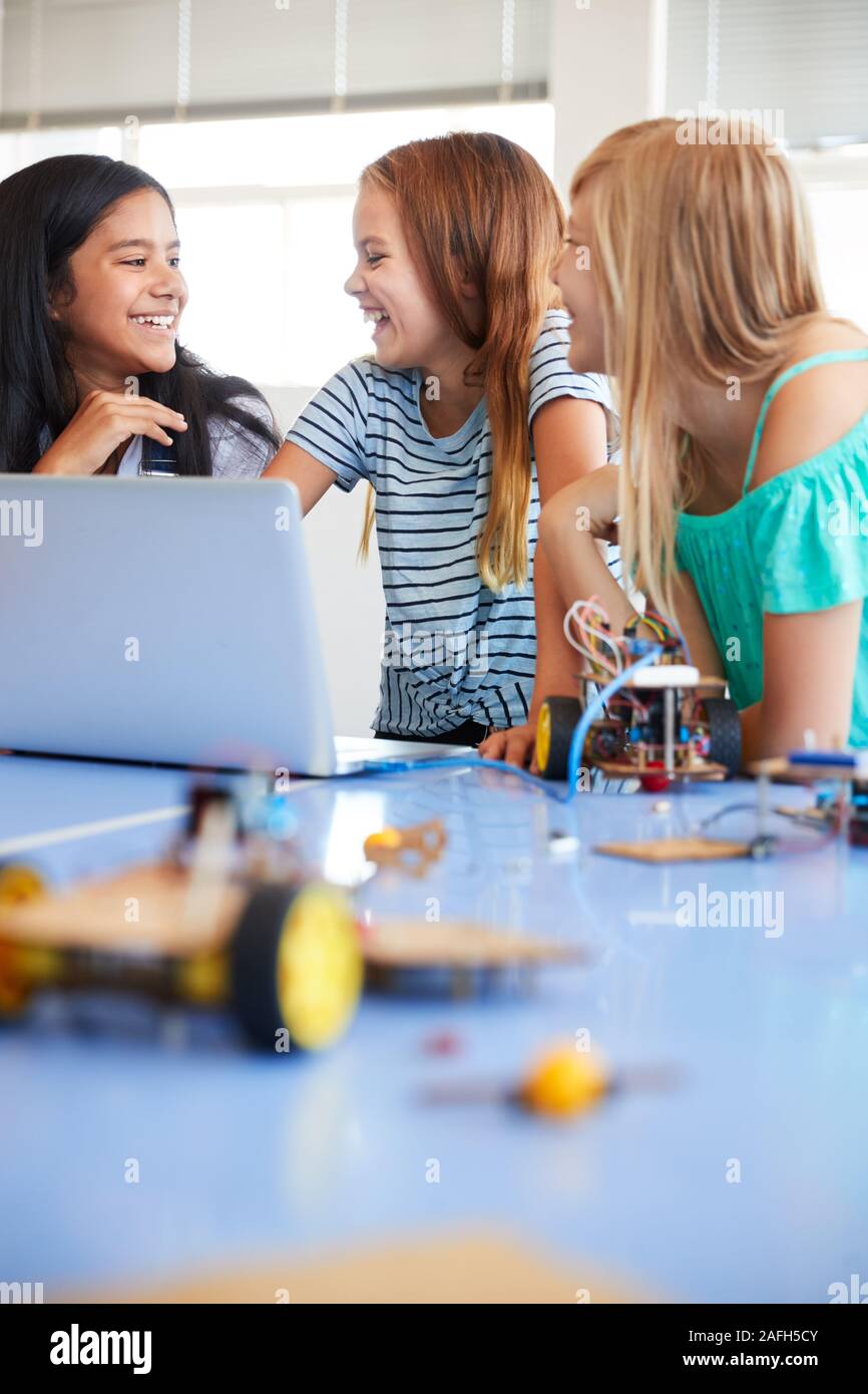 Tre studenti di sesso femminile la costruzione e la programmazione di robot in veicolo dopo la scuola di computer di classe di codifica Foto Stock