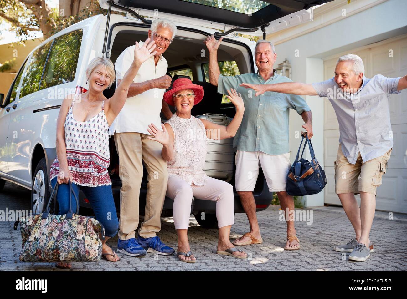 Ritratto di entusiasti amici Senior di carico dei bagagli nel tronco della vettura in procinto di partire per le vacanze Foto Stock