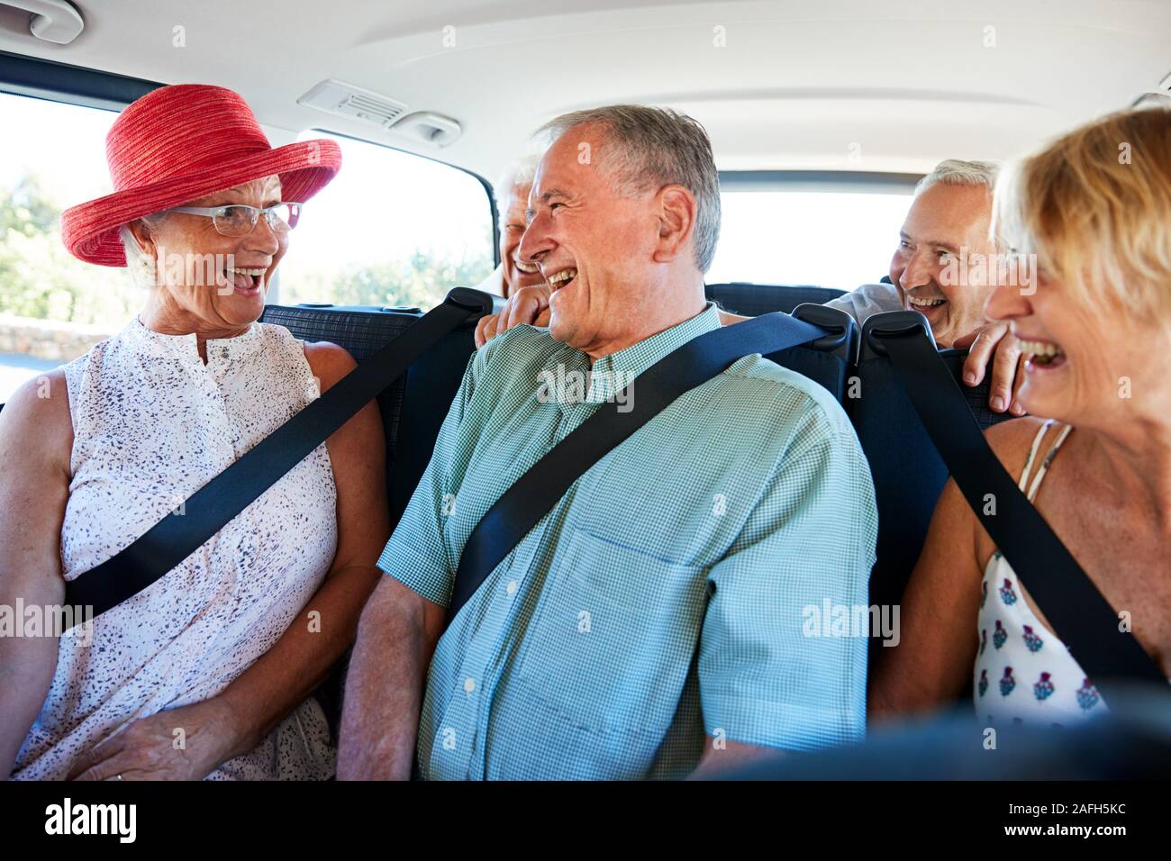 Gruppo di alti amici seduti nel retro del van essendo azionato per vacanza Foto Stock