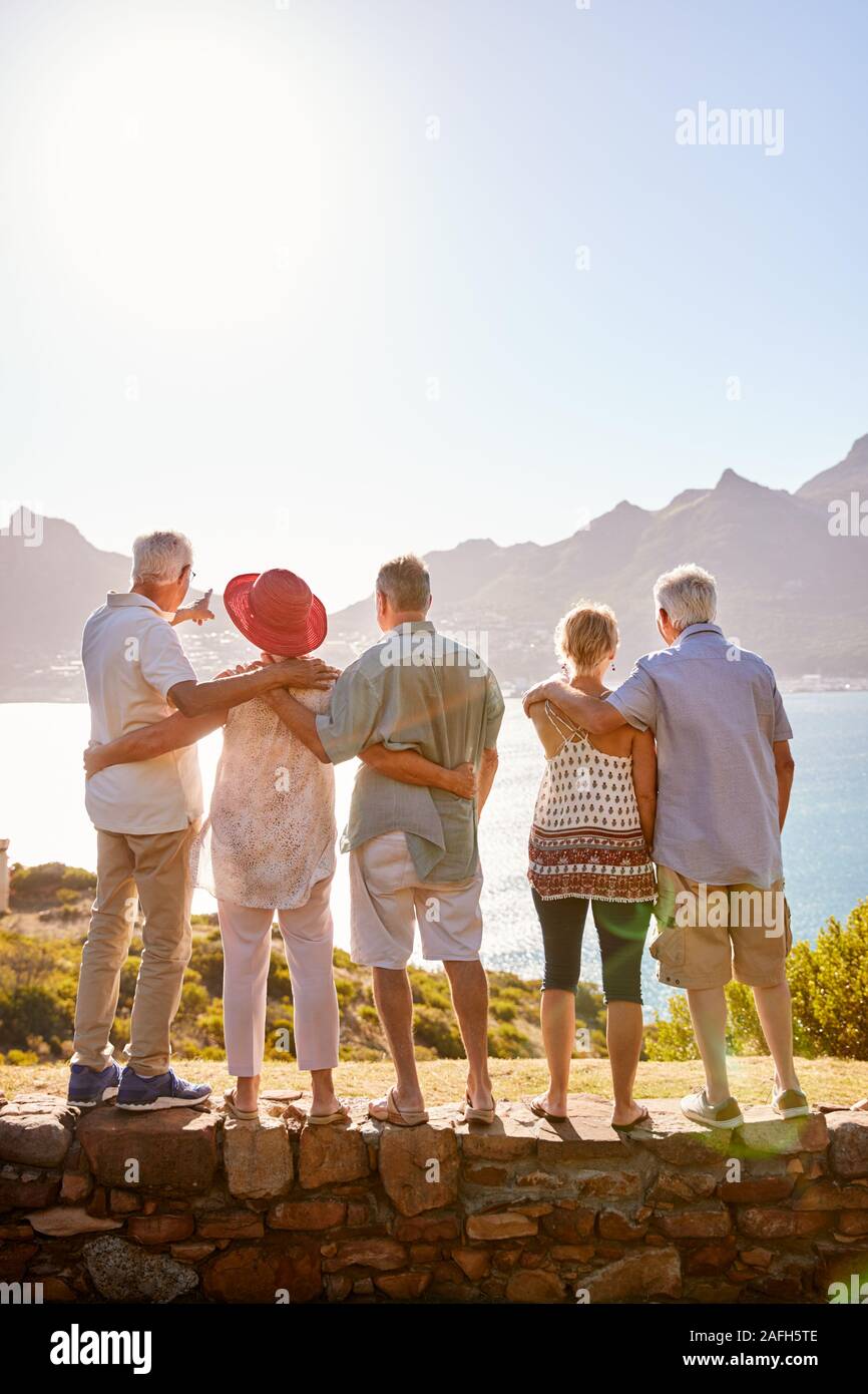 Vista posteriore del Senior amici in visita turistica a Landmark vacanza di gruppo permanente sulla parete Foto Stock