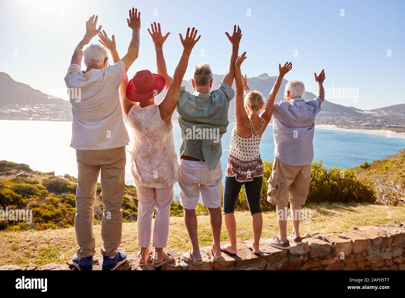 Vista posteriore del Senior amici in visita turistica a Landmark vacanza di gruppo con le braccia sollevate Foto Stock