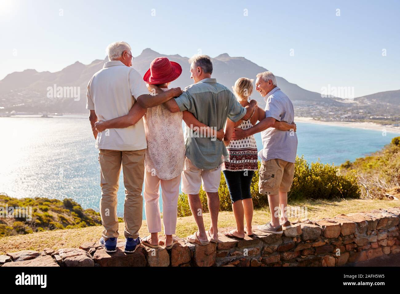 Vista posteriore del Senior amici in visita turistica a Landmark vacanza di gruppo permanente sulla parete Foto Stock