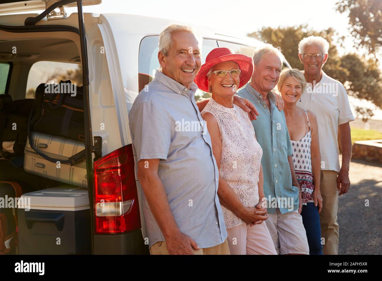 Ritratto di Senior amici insieme in piedi accanto a Van in vacanza Foto Stock