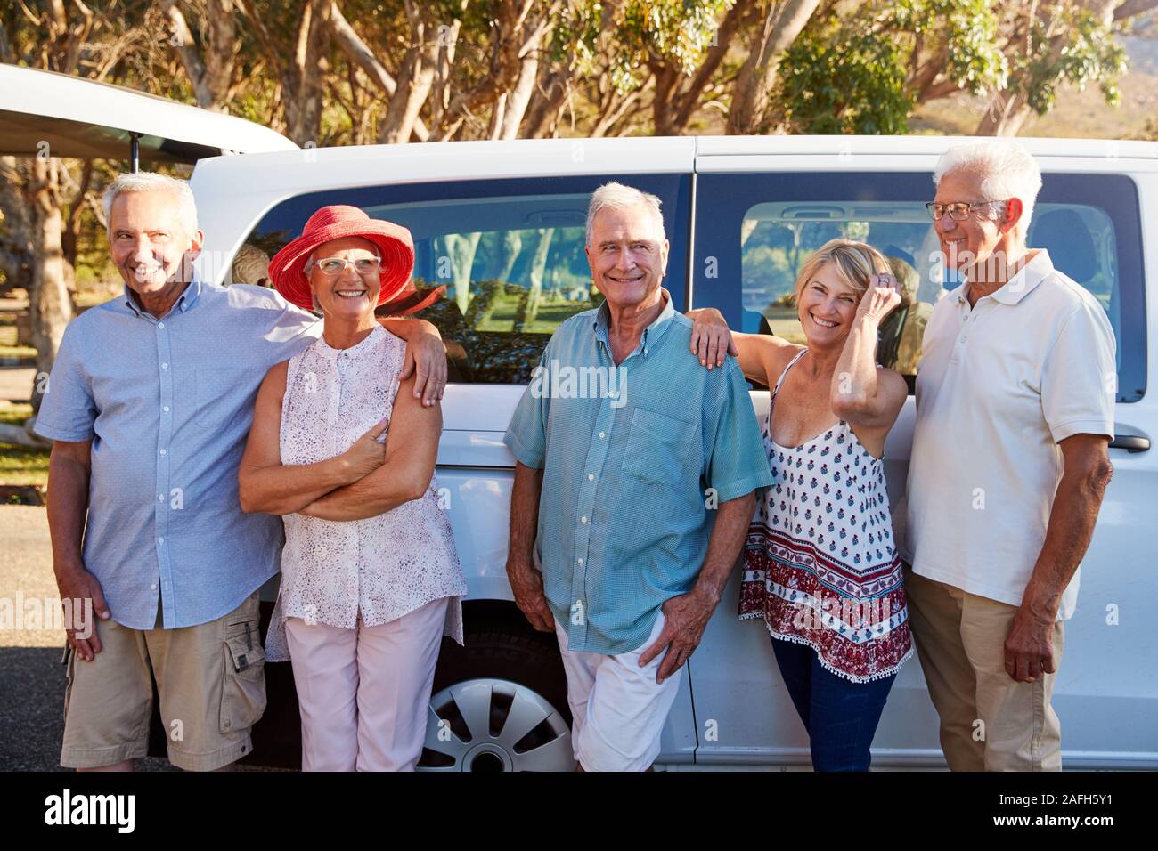 Ritratto di Senior amici insieme in piedi accanto a Van in vacanza Foto Stock