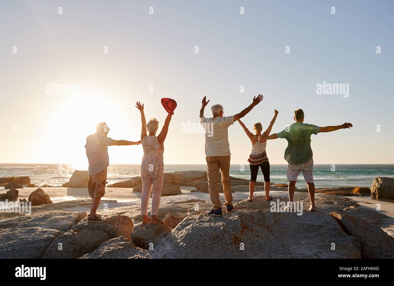 Vista posteriore del Senior amici in piedi sulle rocce in vacanza con le braccia aperte Foto Stock