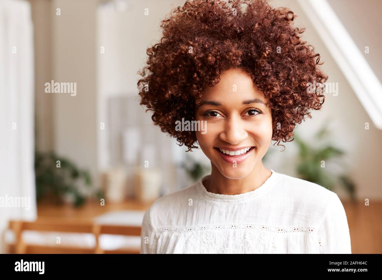 Ritratto di sorridente giovane donna in Appartamento Loft Foto Stock