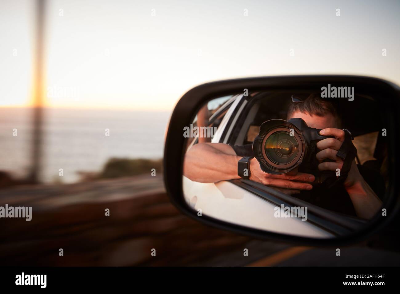 L'uomo con la fotocamera tenendo la foto in auto specchietto laterale Foto Stock