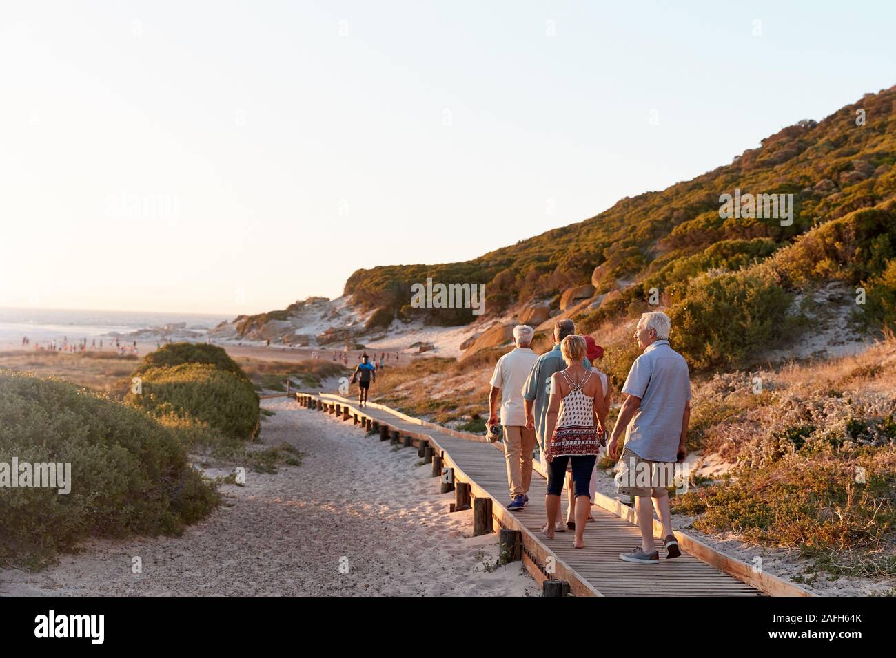Gruppo di amici Senior camminare lungo la passeggiata a mare in spiaggia in estate vacanze di gruppo Foto Stock