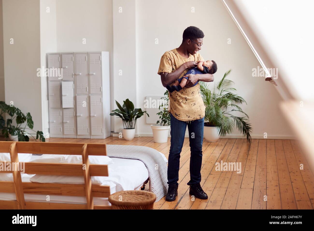 Padre amorevole Holding neonato a casa In Appartamento Loft Foto Stock