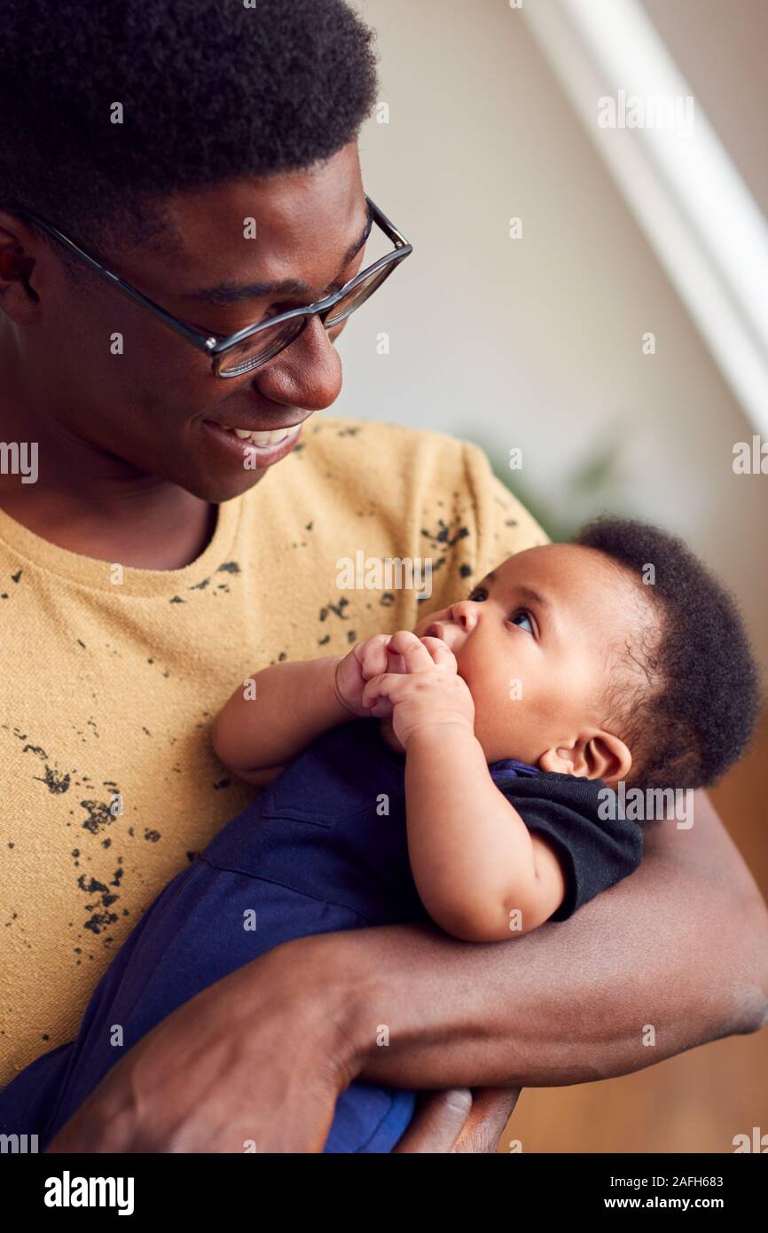 Padre amorevole Holding neonato a casa In Appartamento Loft Foto Stock