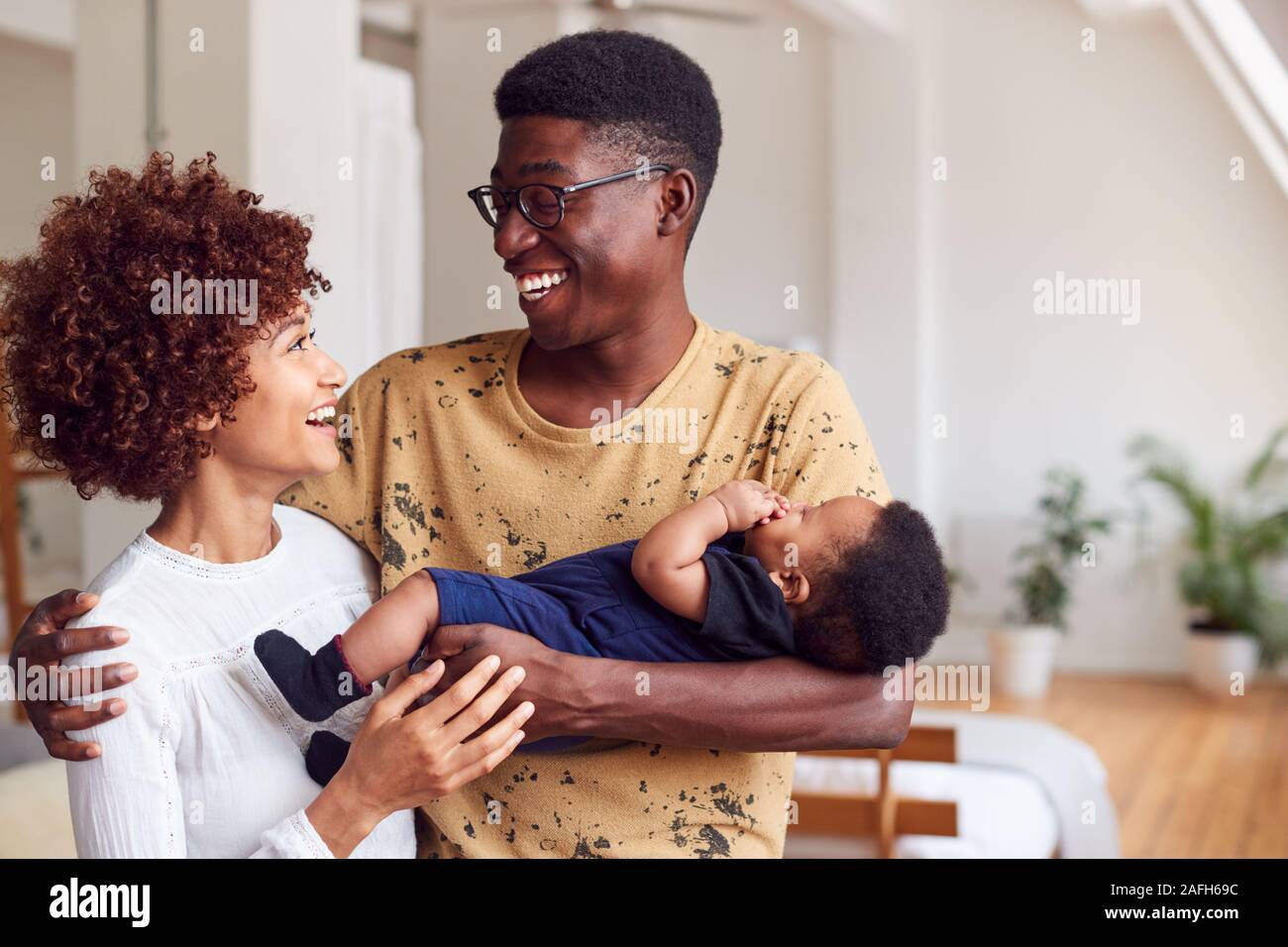 Amare i genitori tenendo neonato a casa In Appartamento Loft Foto Stock