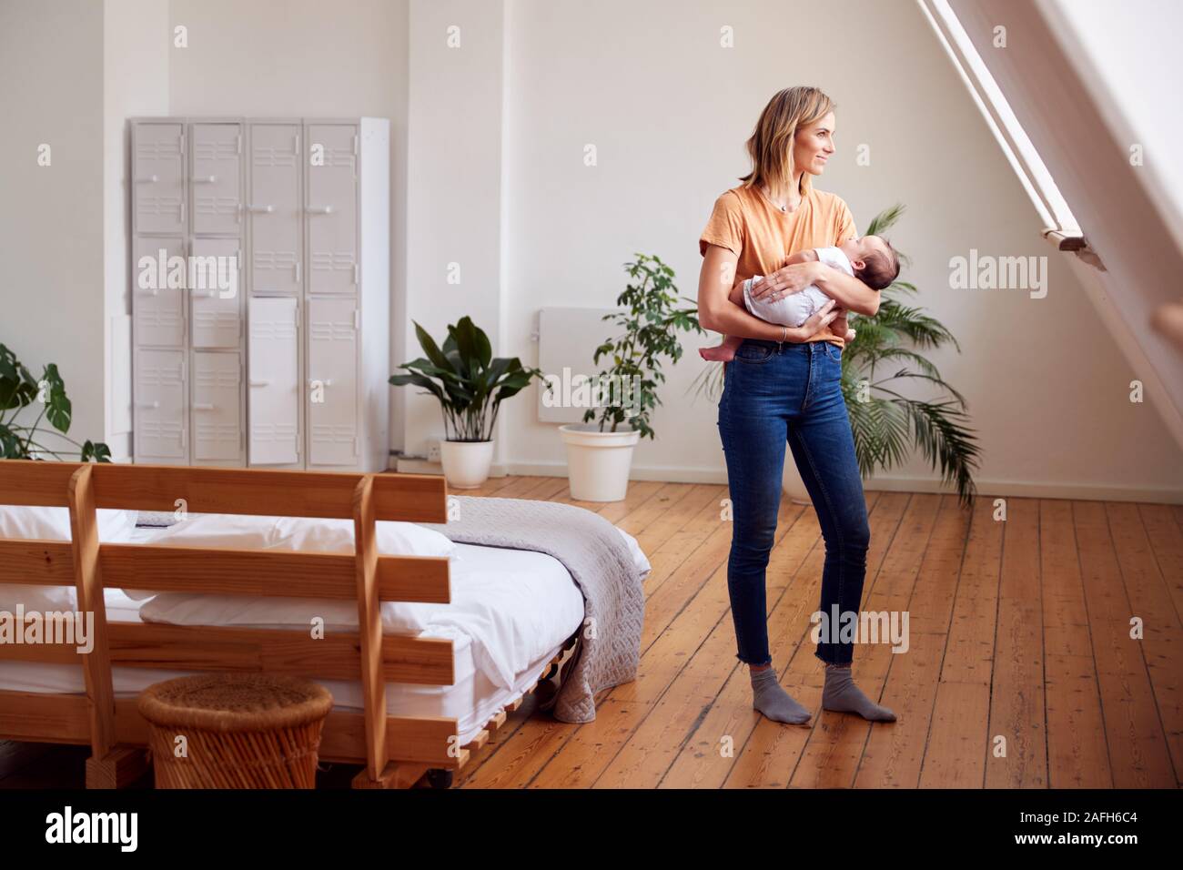 Madre Amorosa azienda neonato a casa In Appartamento Loft Foto Stock