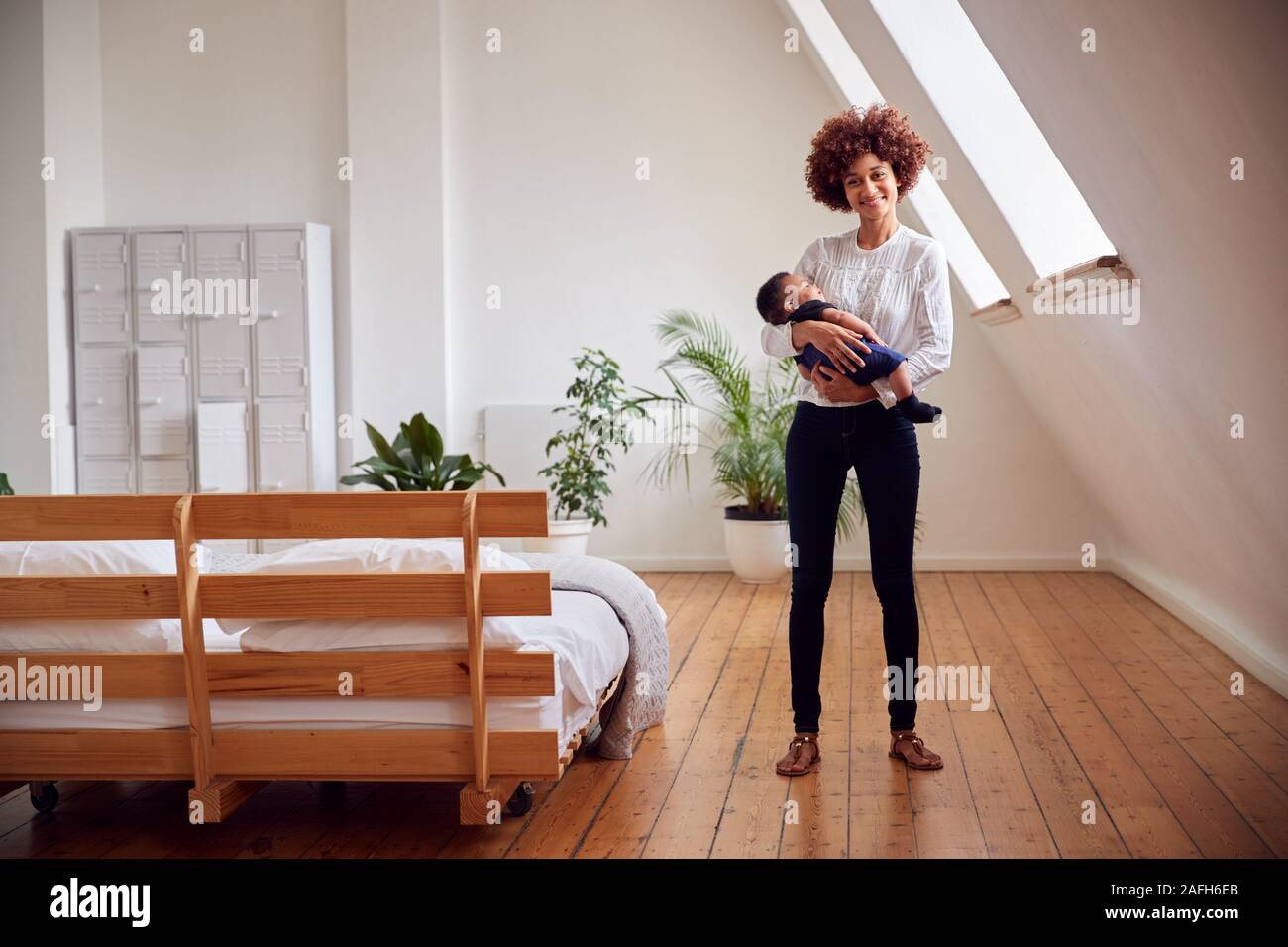 Ritratto di Madre Amorosa azienda neonato a casa In Appartamento Loft Foto Stock