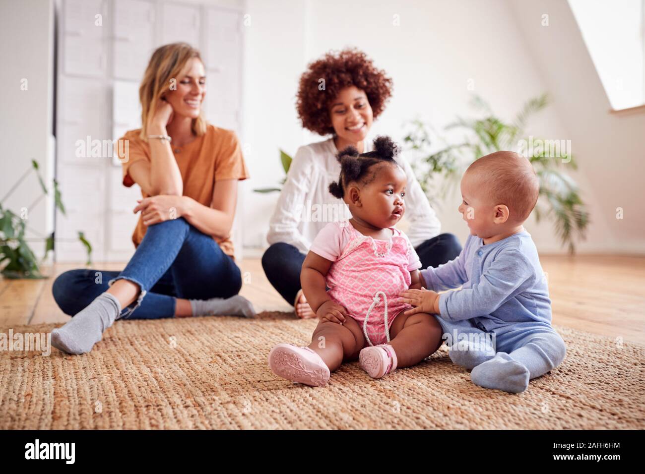 Due madri incontro per data di gioco con i bambini a casa In Appartamento Loft Foto Stock