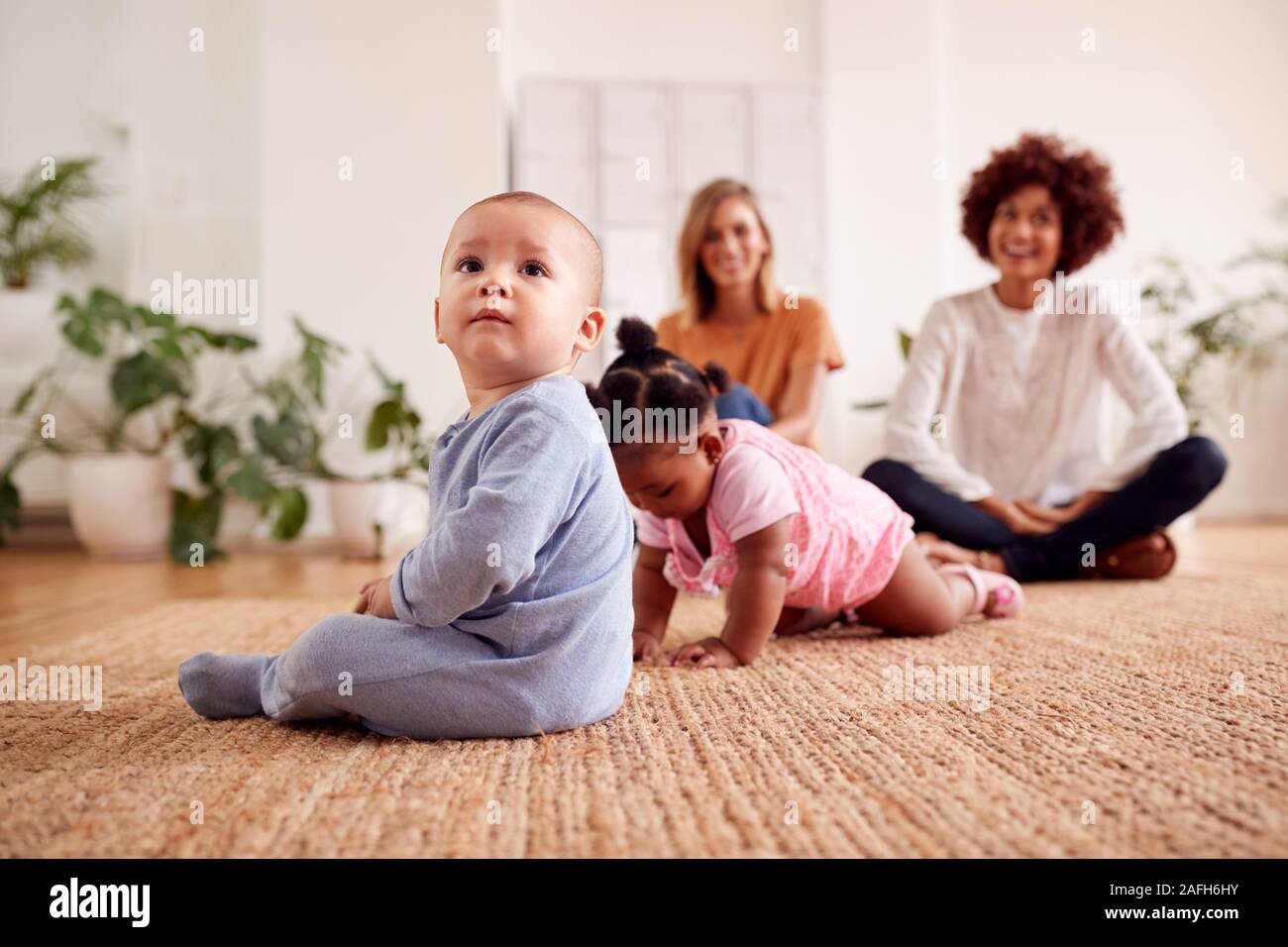 Due madri incontro per data di gioco con i bambini a casa In Appartamento Loft Foto Stock