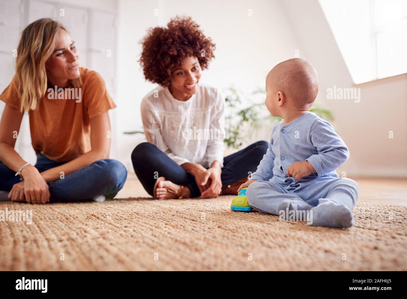 Due madri incontro per data di gioco con i bambini a casa In Appartamento Loft Foto Stock
