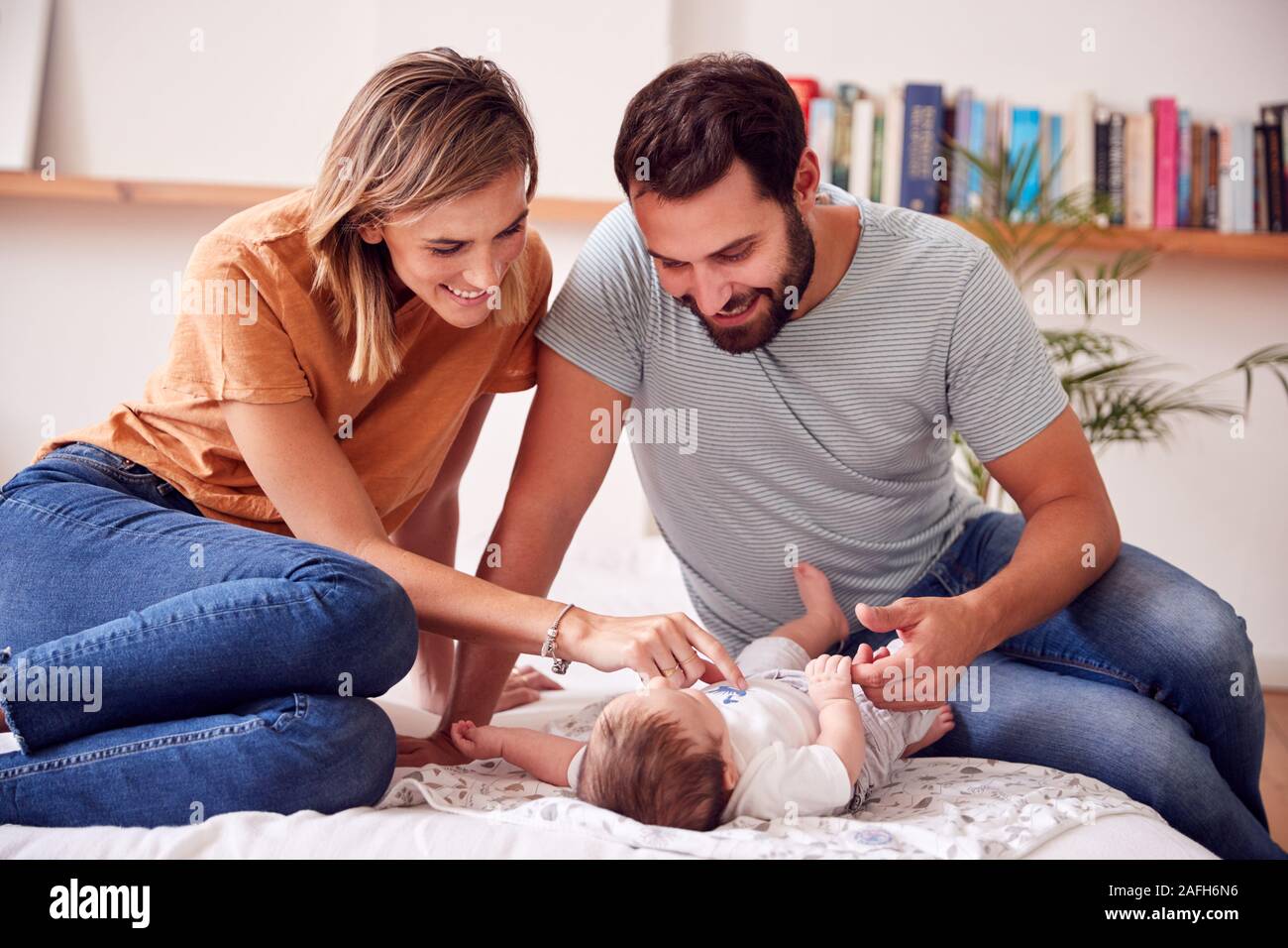 Amare i genitori con bambino neonato sdraiato sul letto di casa in Appartamento Loft Foto Stock