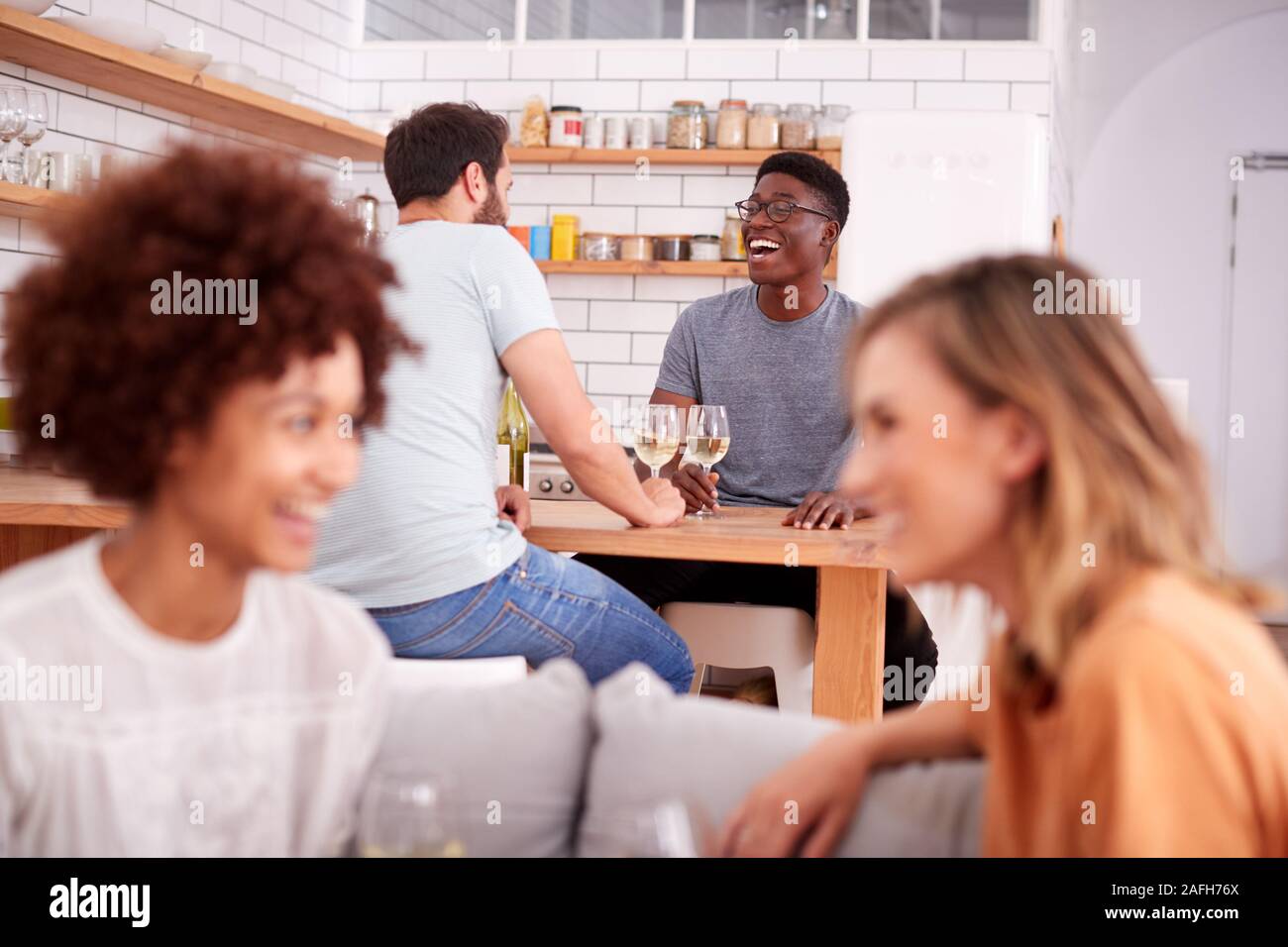 Due coppie relax sul divano di casa con un bicchiere di vino a parlare insieme Foto Stock