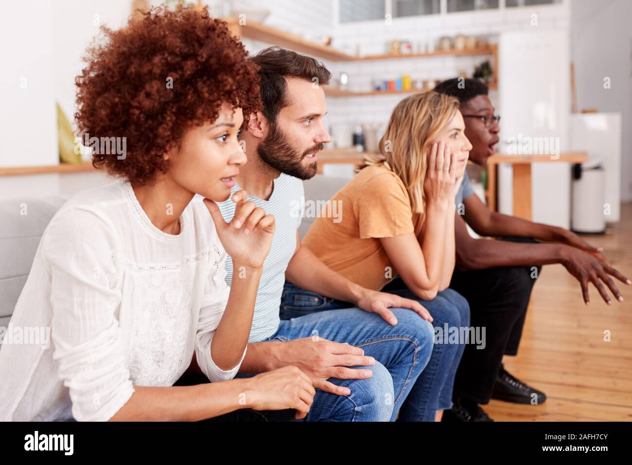 Eccitato Gruppo di amici seduti sul divano e guardare lo sport in TV Foto Stock