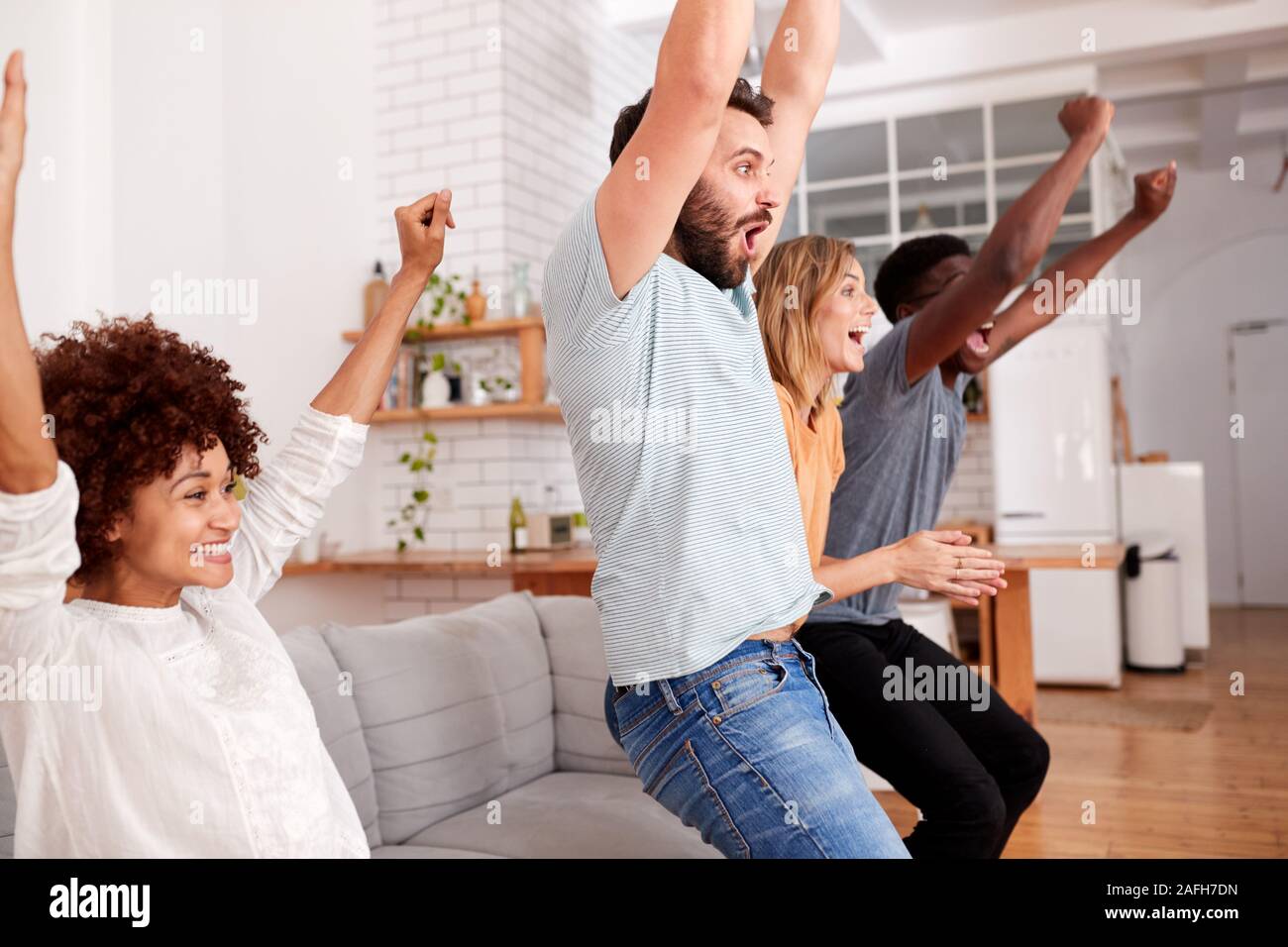 Eccitato Gruppo di amici seduti sul divano a guardare lo sport in TV e celebrando Foto Stock