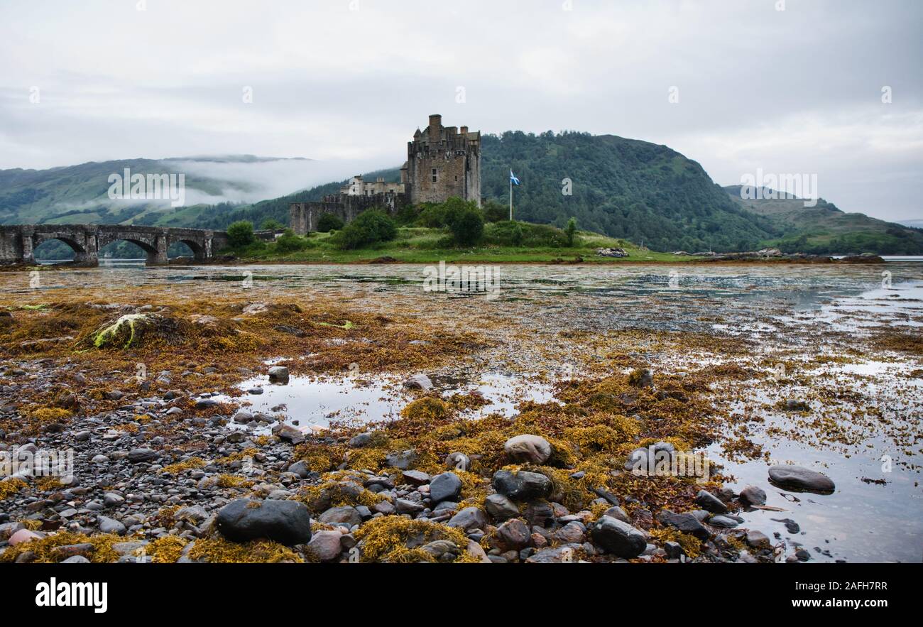 Castello di Eilean Donan e ponte pedonale tra il muso paesaggio di loch all'alba, Western Highlands, Scozia Foto Stock