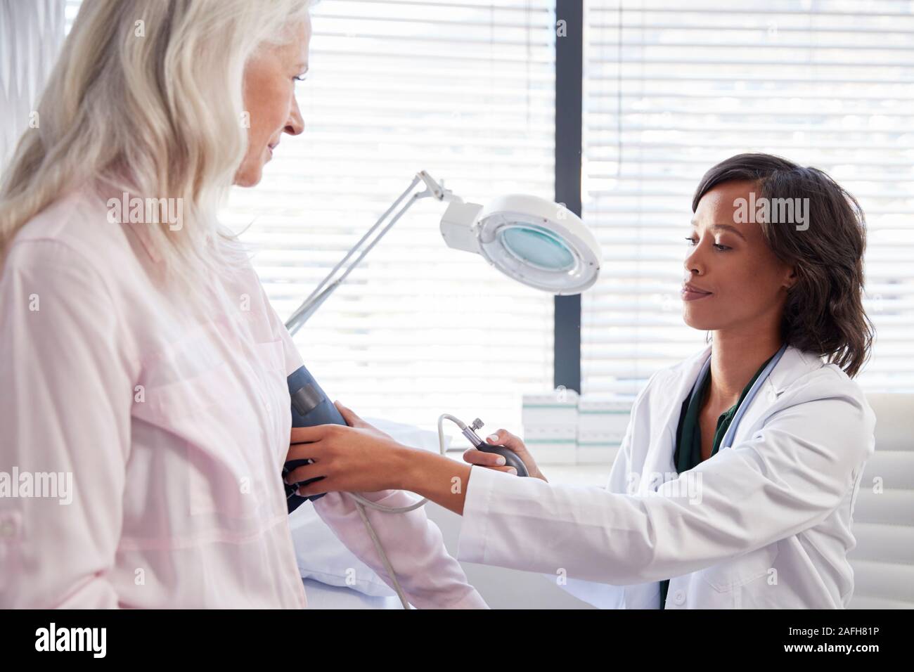 Donna paziente avente la pressione del sangue presa dal medico donna in Office Foto Stock