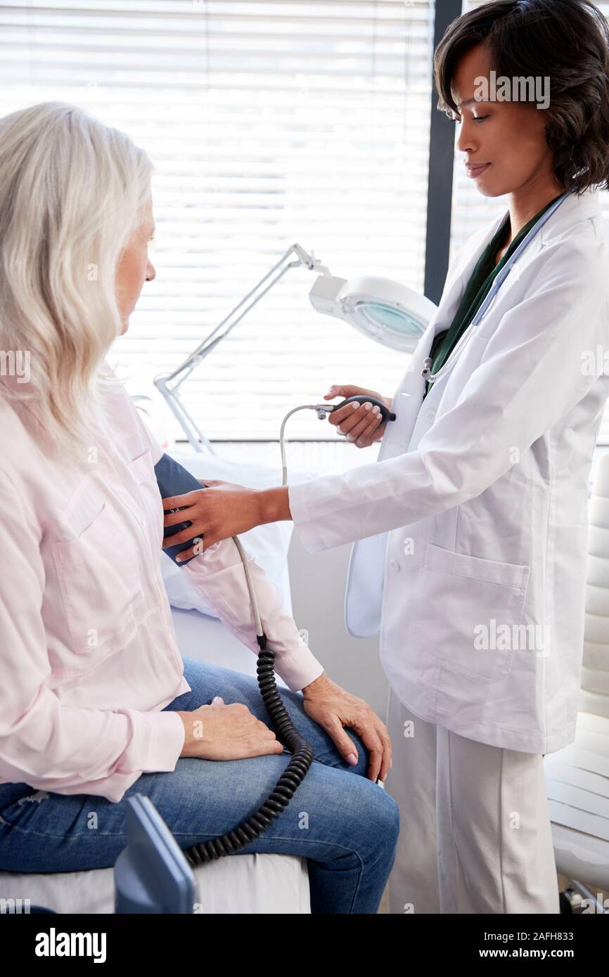 Donna paziente avente la pressione del sangue presa dal medico donna in Office Foto Stock