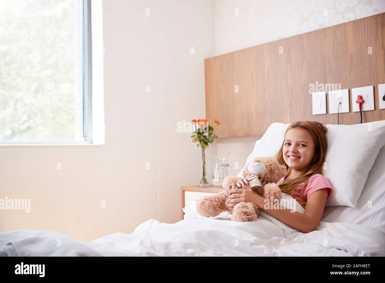 Ritratto di ragazza distesa nel letto di ospedale abbracciando Teddy Bear Foto Stock