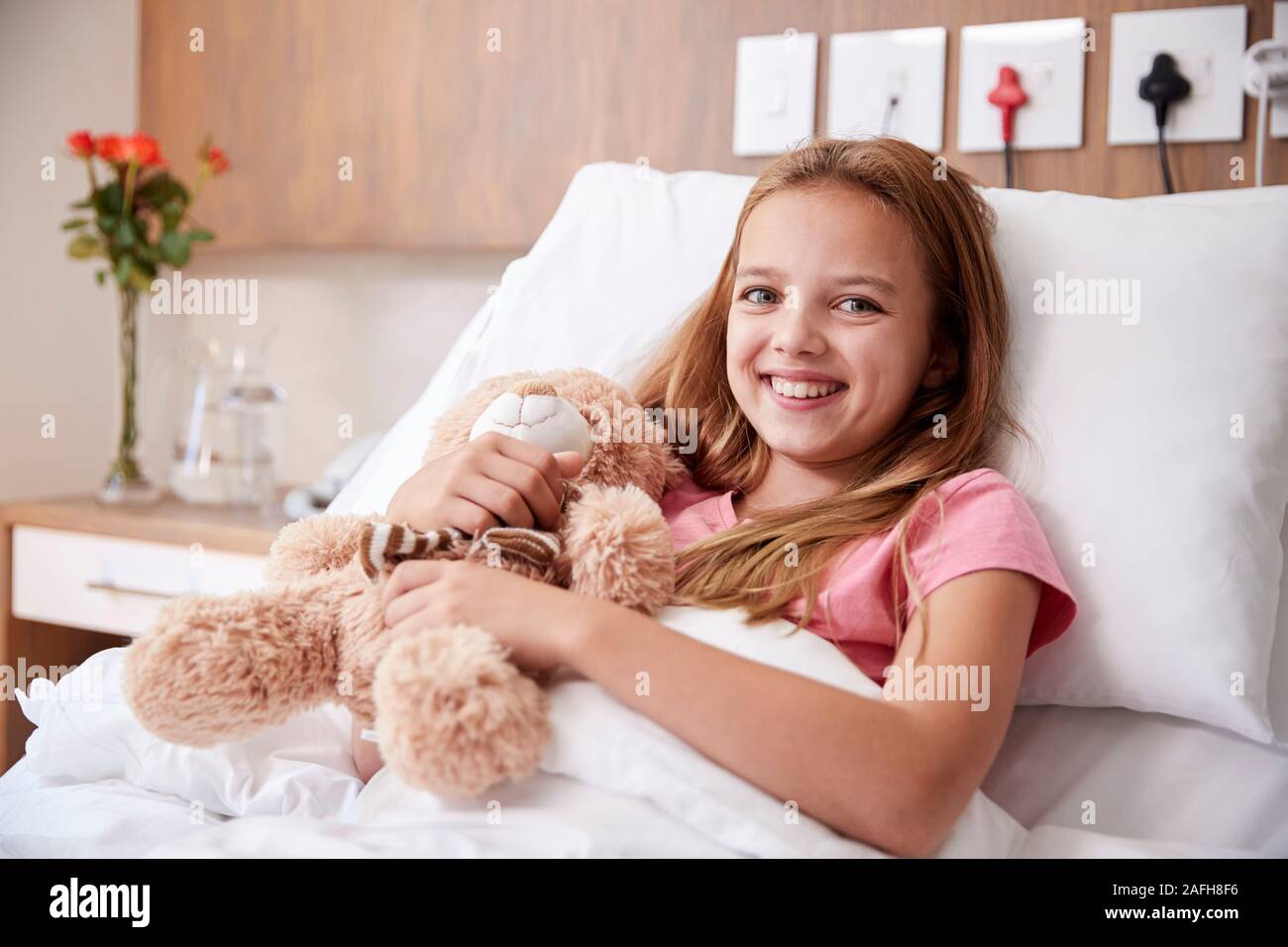 Ritratto di ragazza distesa nel letto di ospedale abbracciando Teddy Bear Foto Stock