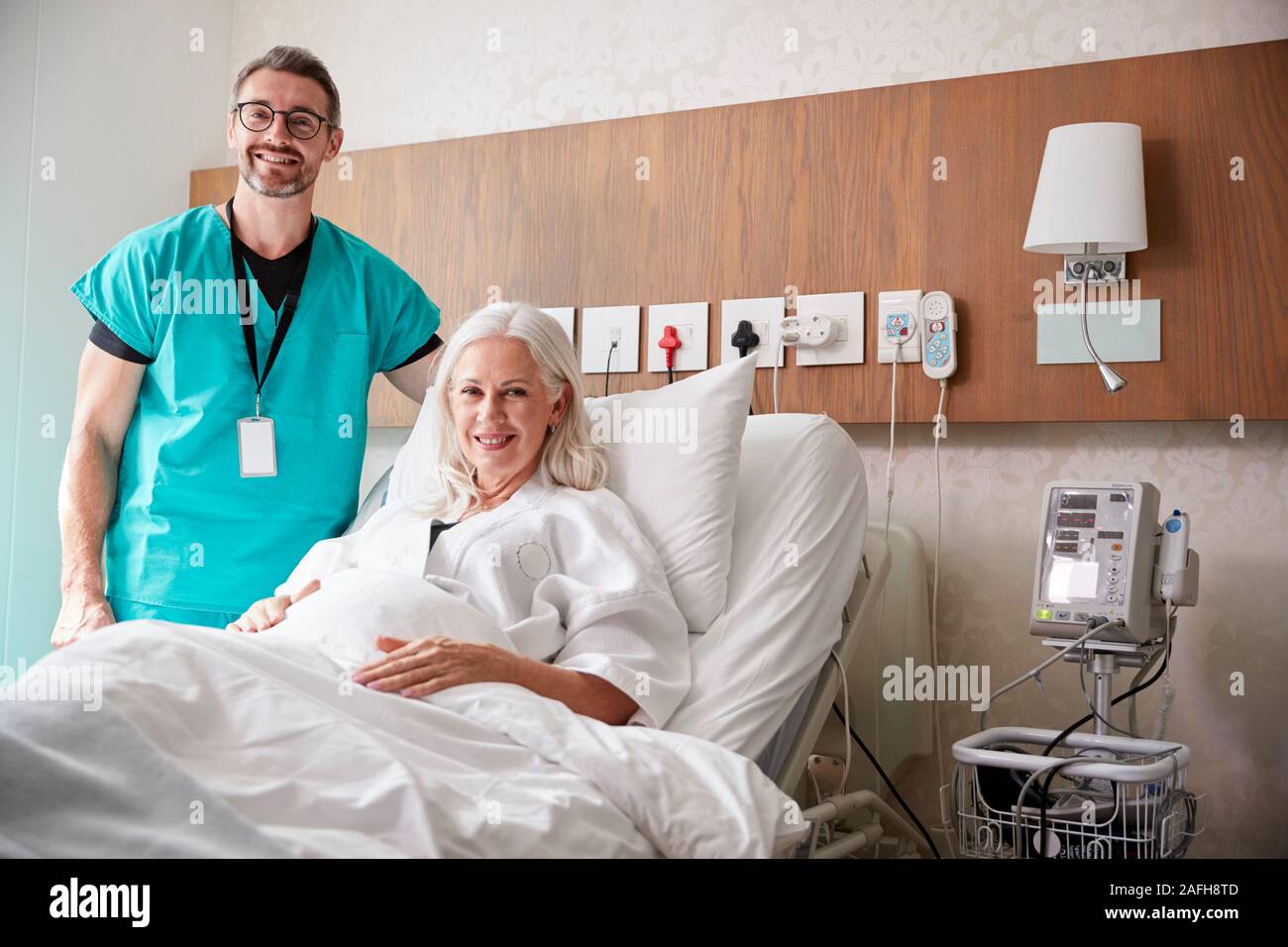 Ritratto di chirurgo visitando femmina matura paziente nel letto di ospedale Foto Stock
