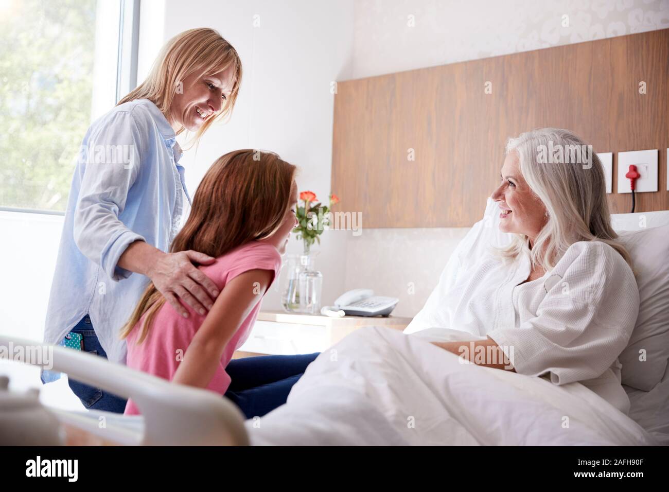 Nipote di parlare con la Nonna sulla famiglia visita all'ospedale Foto Stock