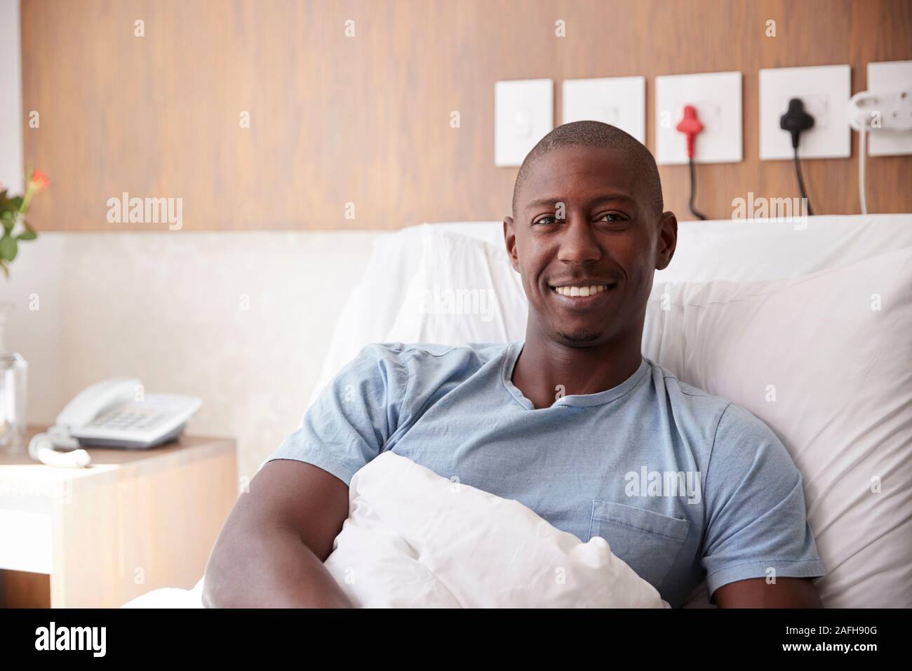 Ritratto del paziente di sesso maschile che giace nel letto di ospedale sorridente in telecamera Foto Stock